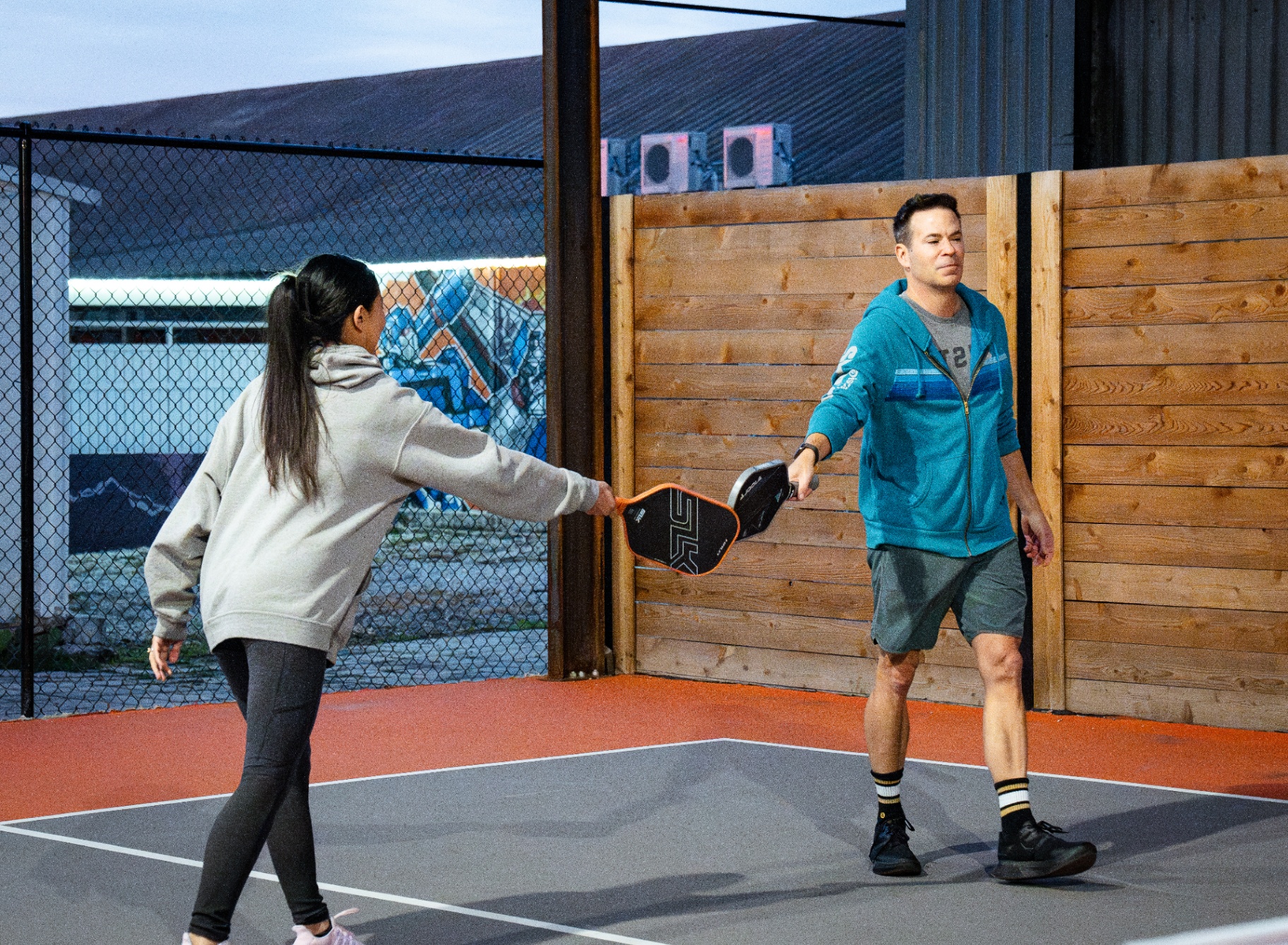 Two players tapping paddles at the net after a rally